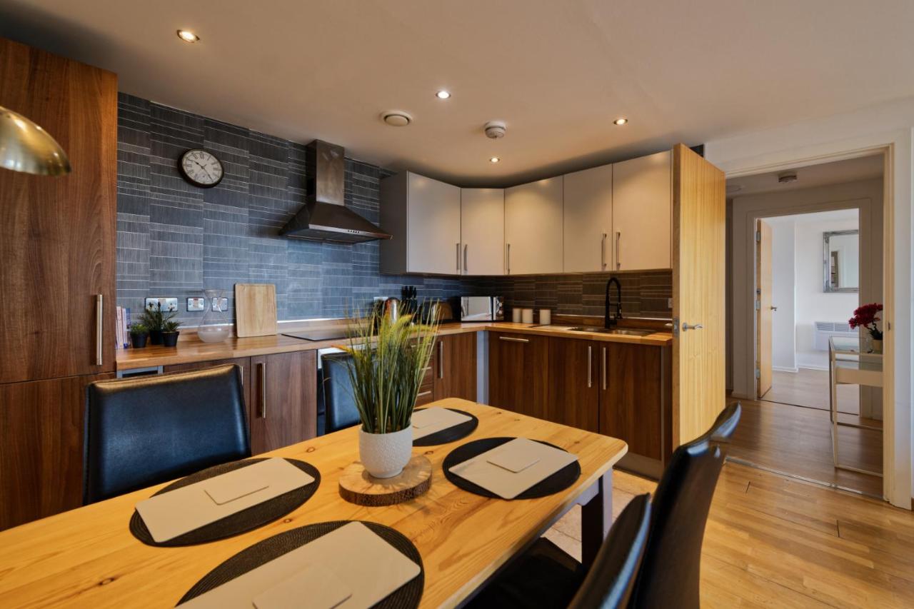 Kitchen and dining area with a wooden table and chairs at Sidemersey Livings apartment in Liverpool city centre